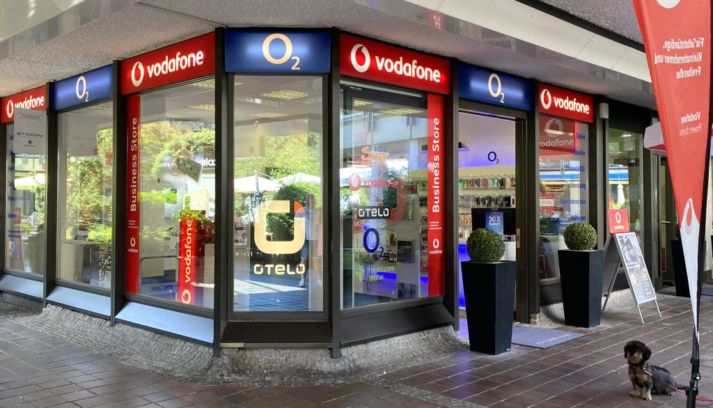 Fassade eines Vodafone und O2 Geschäftslokals mit Schaufenstern und Logo.
